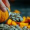 Pumpkin Seeds in Spoon with Whole and Sliced Pumpkins