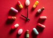 Medication Time Concept Pills Arranged as Clock Face on Red Background, Healthcare Schedule and Reminder