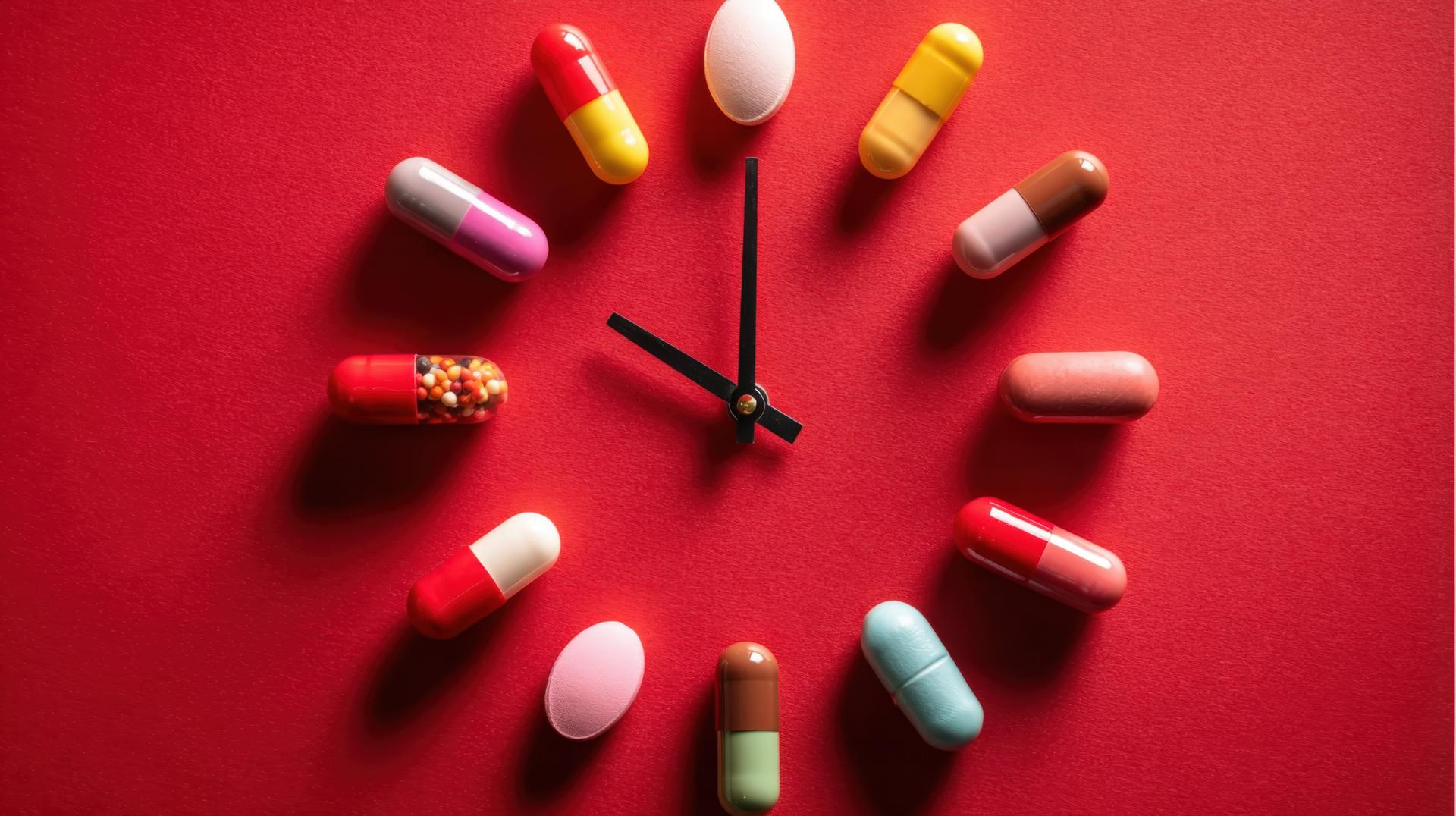 Medication Time Concept Pills Arranged as Clock Face on Red Background, Healthcare Schedule and Reminder