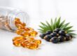 Close-up stock photo of saw palmetto berries, green leaves, and supplement capsules on a white surface, with a clear medicine bottle, representing ingredients discussed for prostate health and BPH.